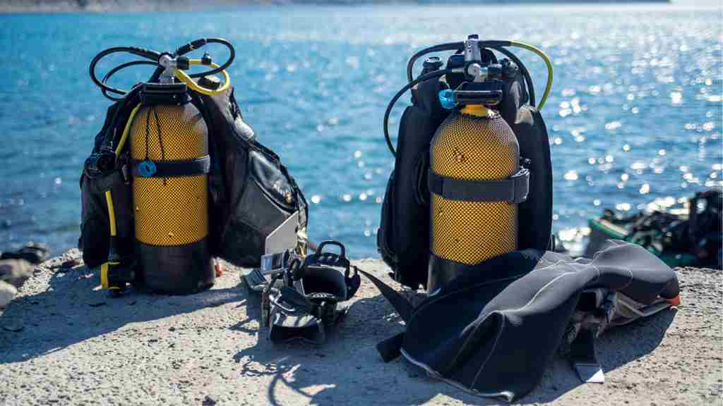 青く光り輝く海面を背景に黄色の酸素ポンべとウェットスーツが2つずつ並んでいる画像