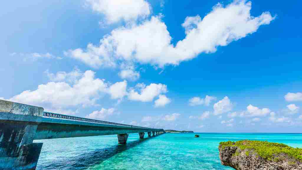 青空が広がりエメラルドグリーンの海に長大橋がかかっている画像