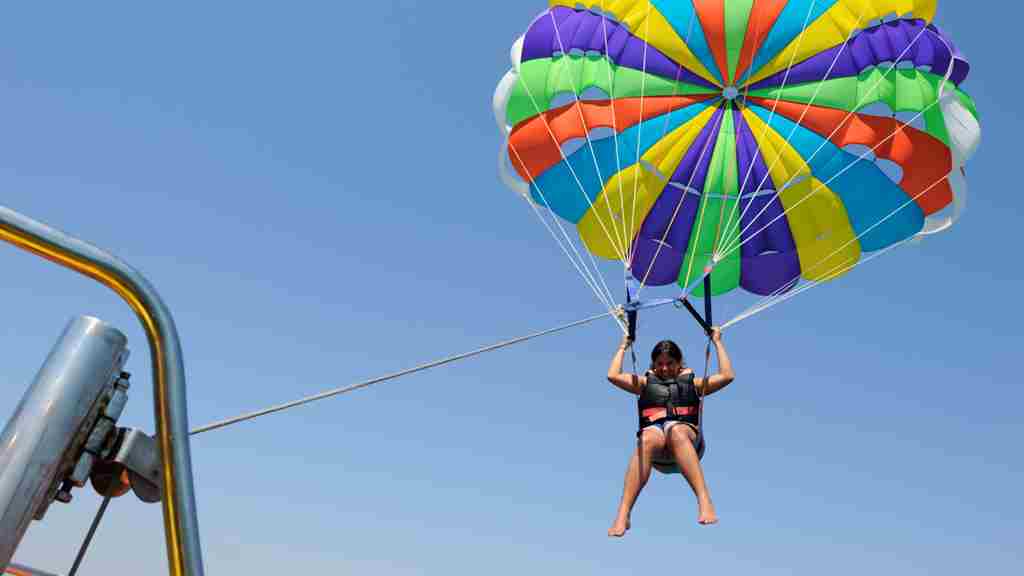 女性1人が大空を背景にカラフルなパラソルのパラセーリングをしている画像