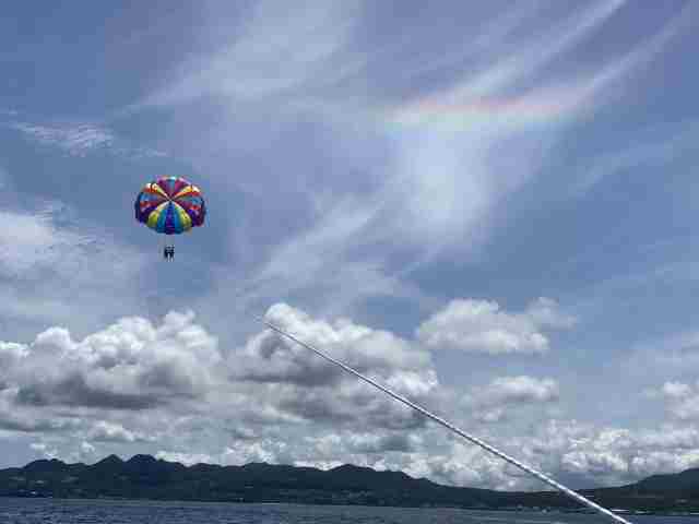 虹がうっすら見える空の中パラセーリングでフライトしてる画像